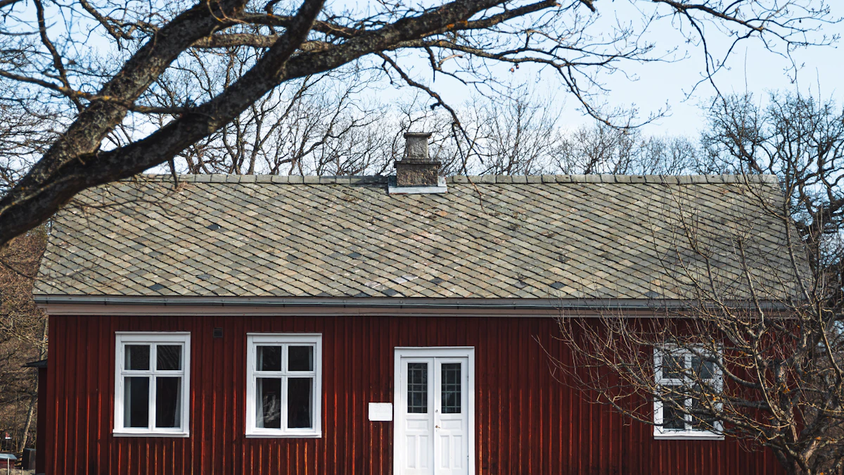 Rött trähus med vita fönsterfoder, fotograferat genom kala trädgrenar